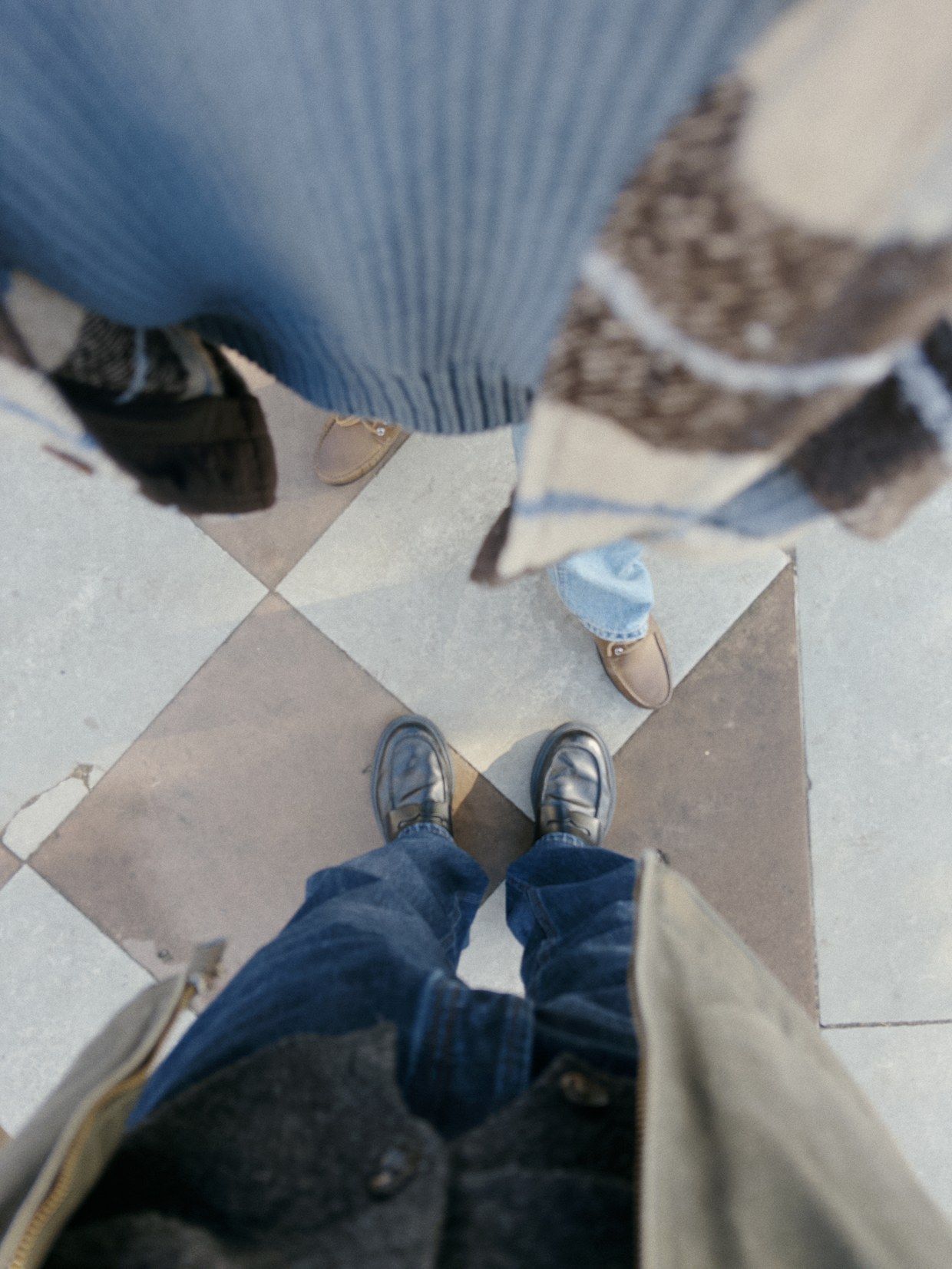 Looking down at shoes on a chequered floor, taken with sunday: softer, deeper and grainy.