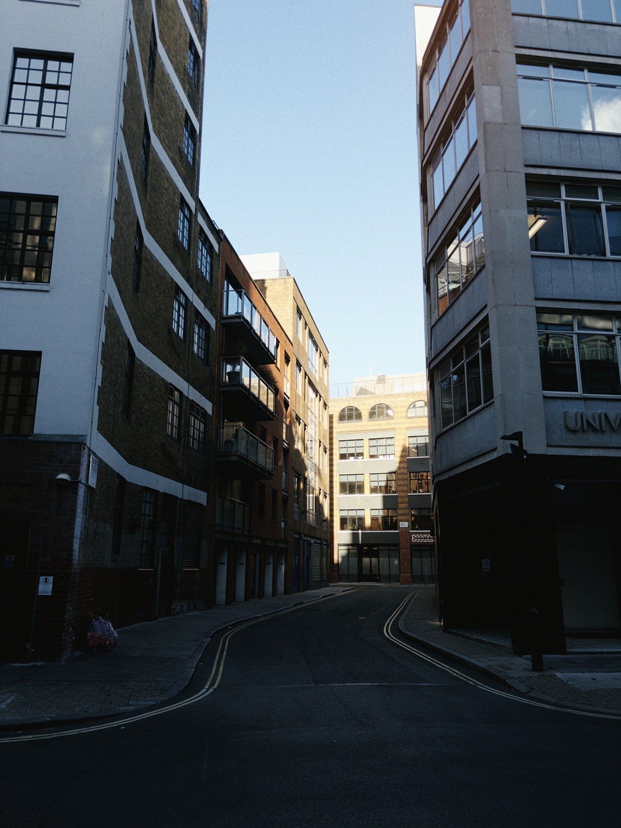 A city street between tall buildings, taken with sunday: softer, deeper and grainy.