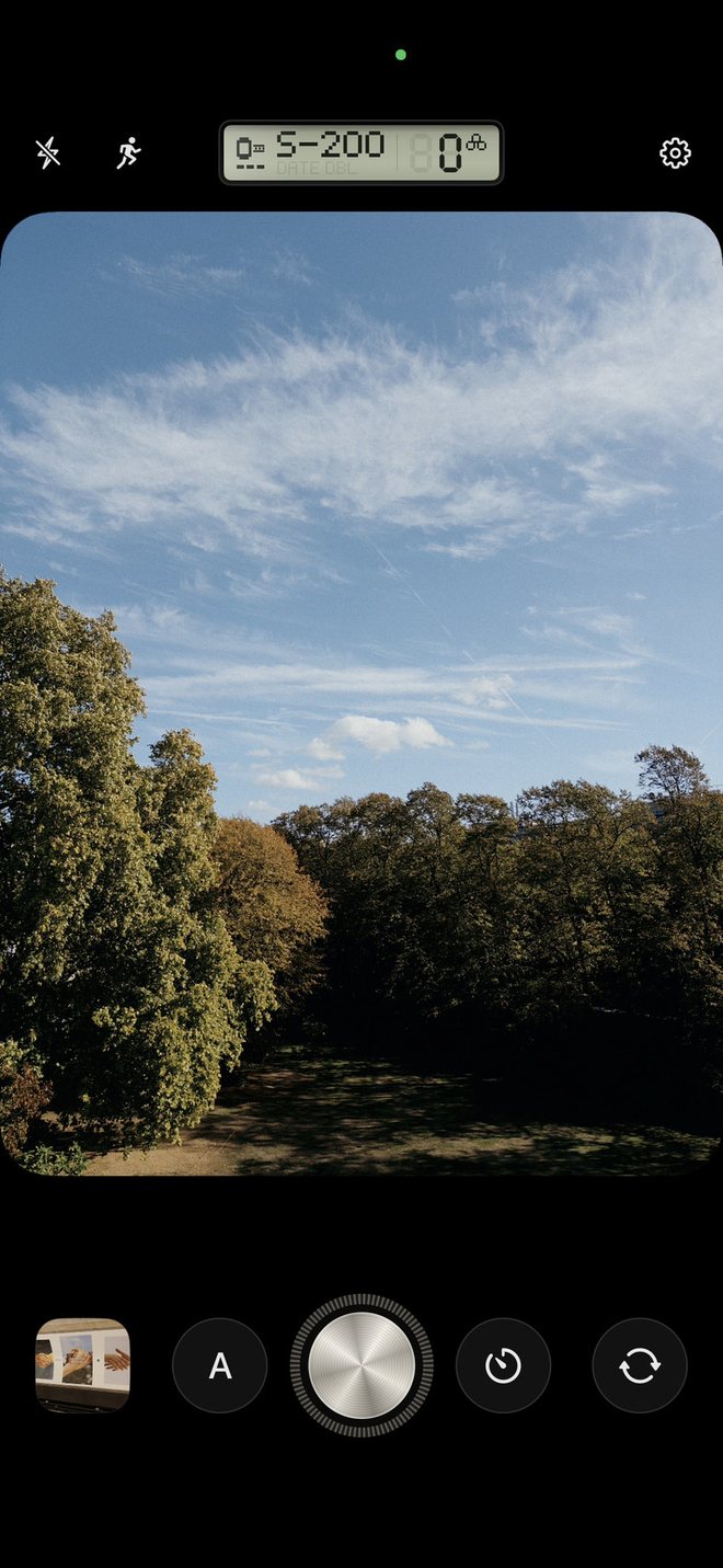 The camera: a park under a wide sky in the viewfinder, a small display saying S-200, and a round metal shutter button.